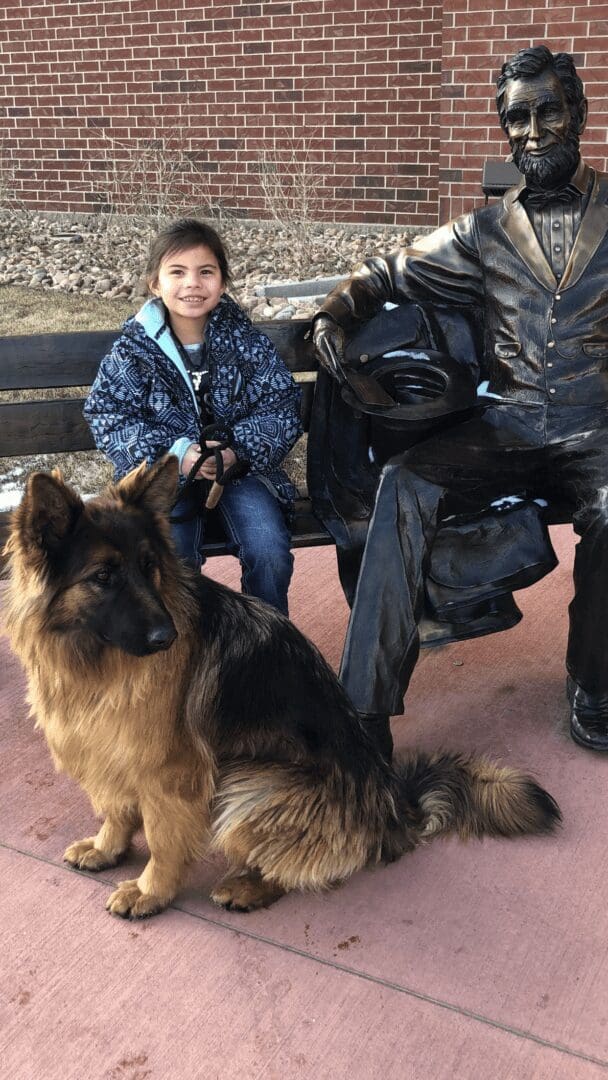 Girl beside bronze statue with long-haired dog